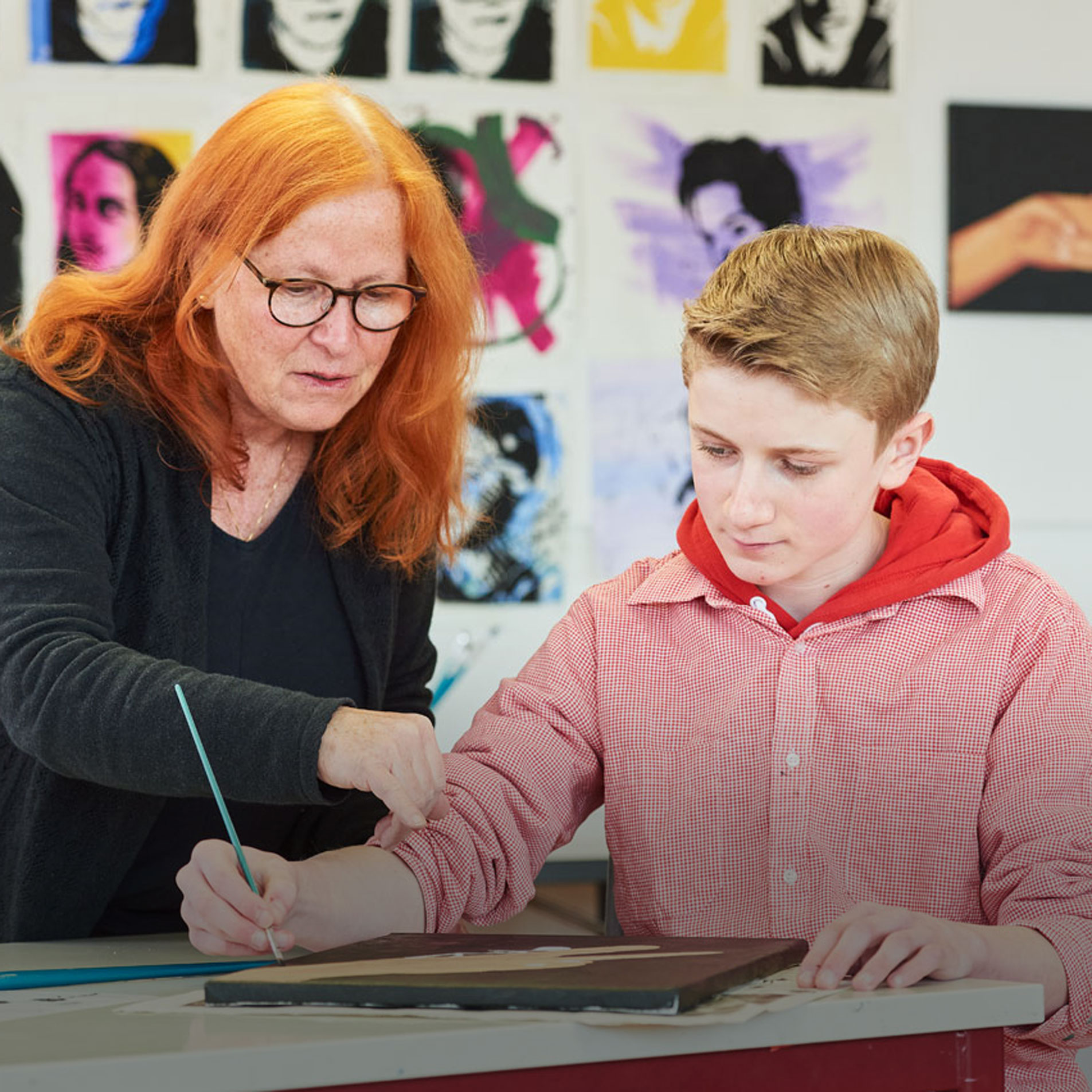 Eine Frau hilft einem Schüler bei einem Kunstprojekt