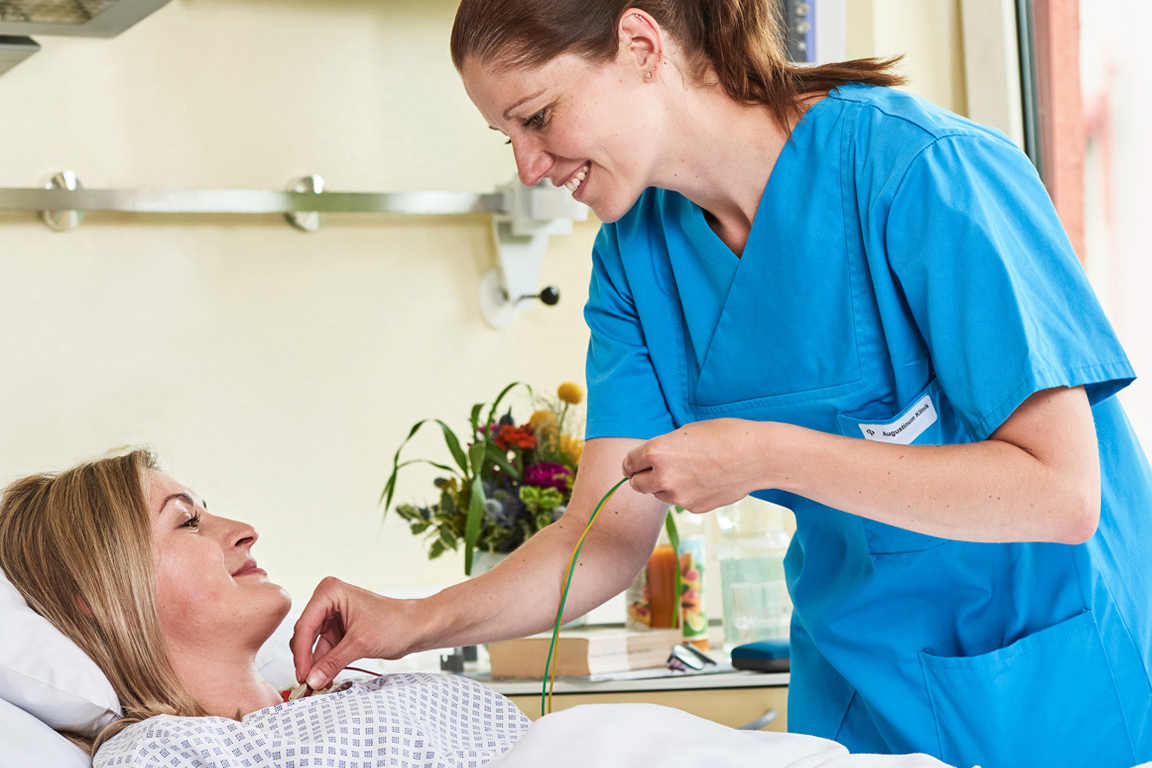 Eine Mitarbeiterin der Augustinum Klinik versorgt einer Patientin 