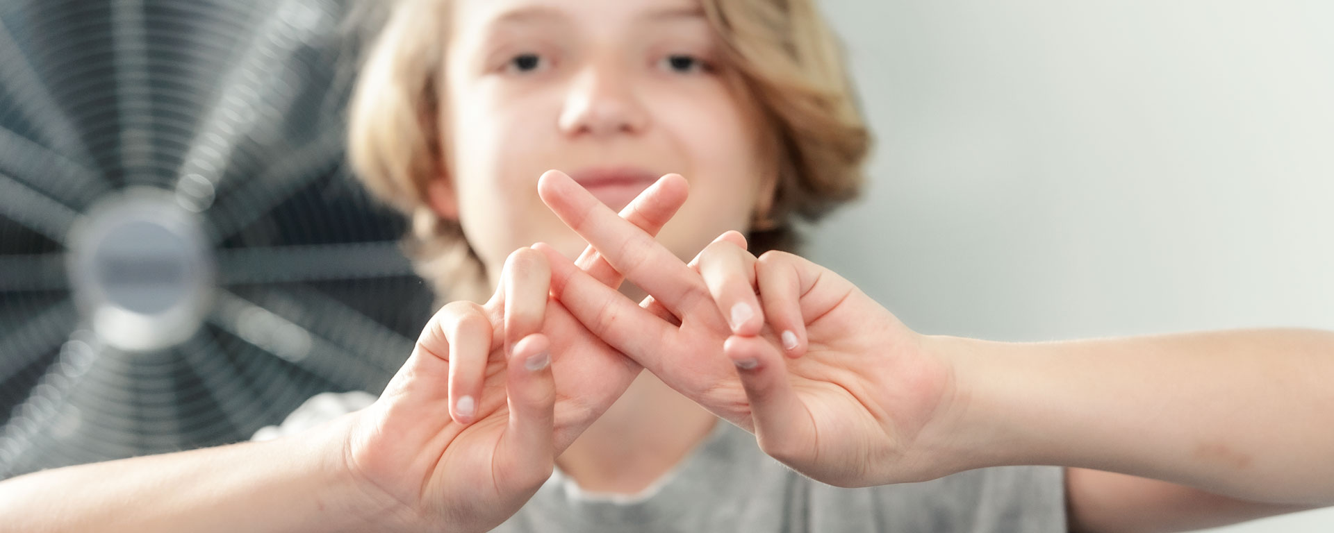 Ein Junge legt zwei Finger beider Hände übereinander