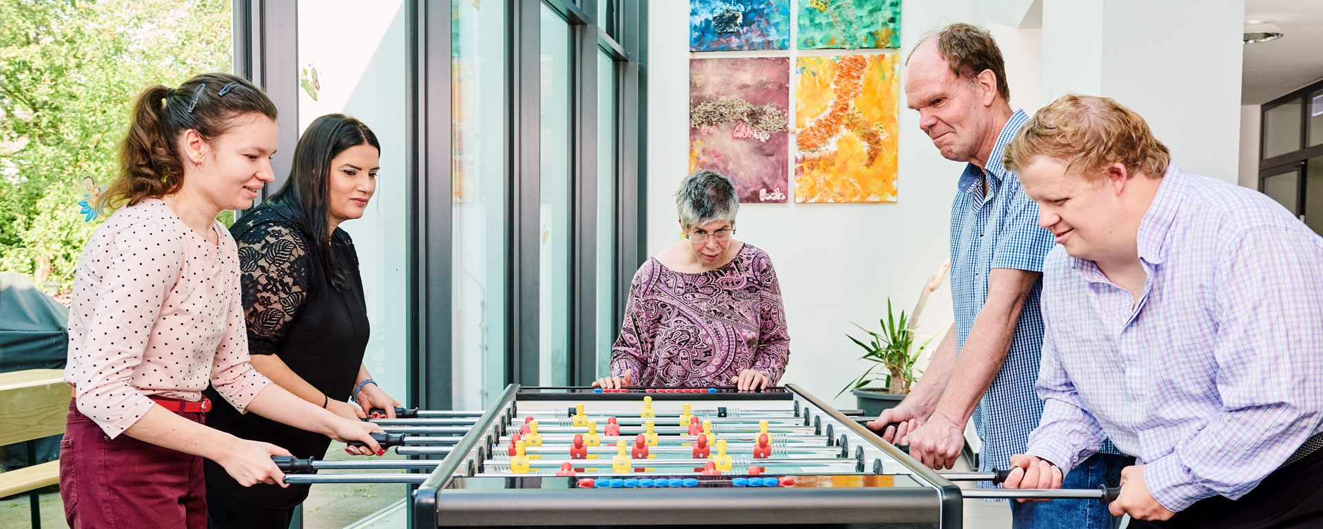 Fünf Bewohner*innen der Augustinum Wohnstätten spielen gemeinsam Tischkicker