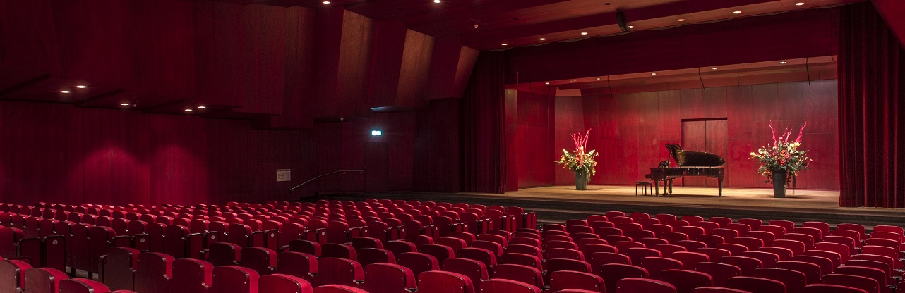 Blumen und ein Konzertflügel auf der Bühne im Theatersaal
