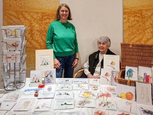 Kartenstand am Adventsmarkt; im Hintergrund die Verkäuferinnen