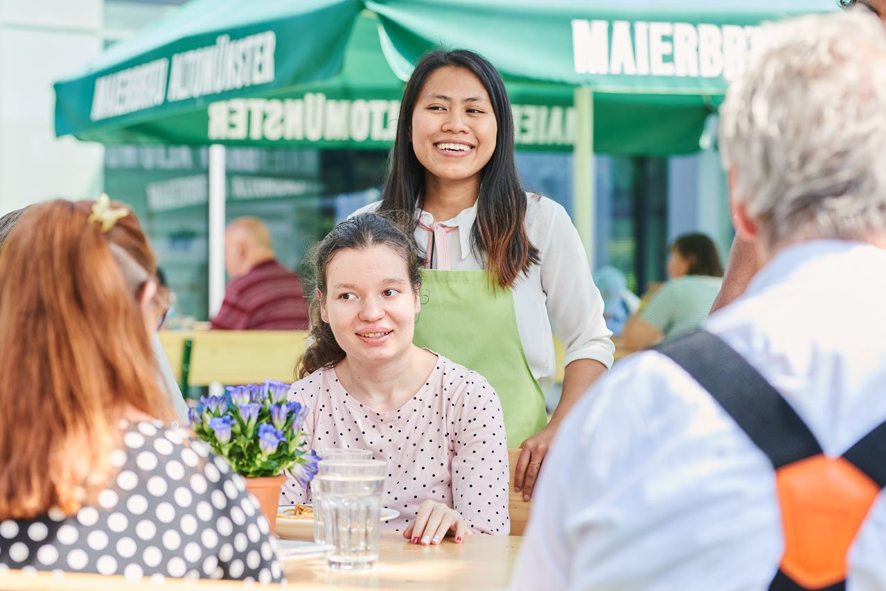Eine Gruppe von Bewohner*innen sitzen an einem Tisch im Freien