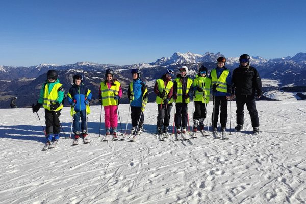 Schüler*innen stehen auf einer Skipiste und lächeln in die Kamera