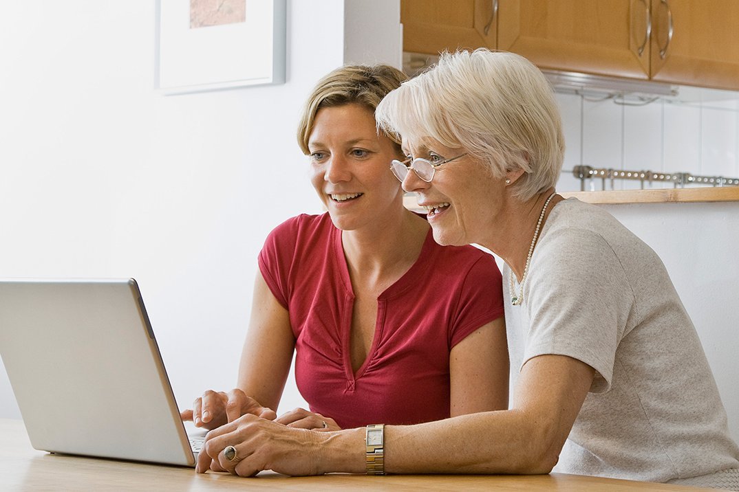 Eine Frau hilft einer Seniorin am Laptop