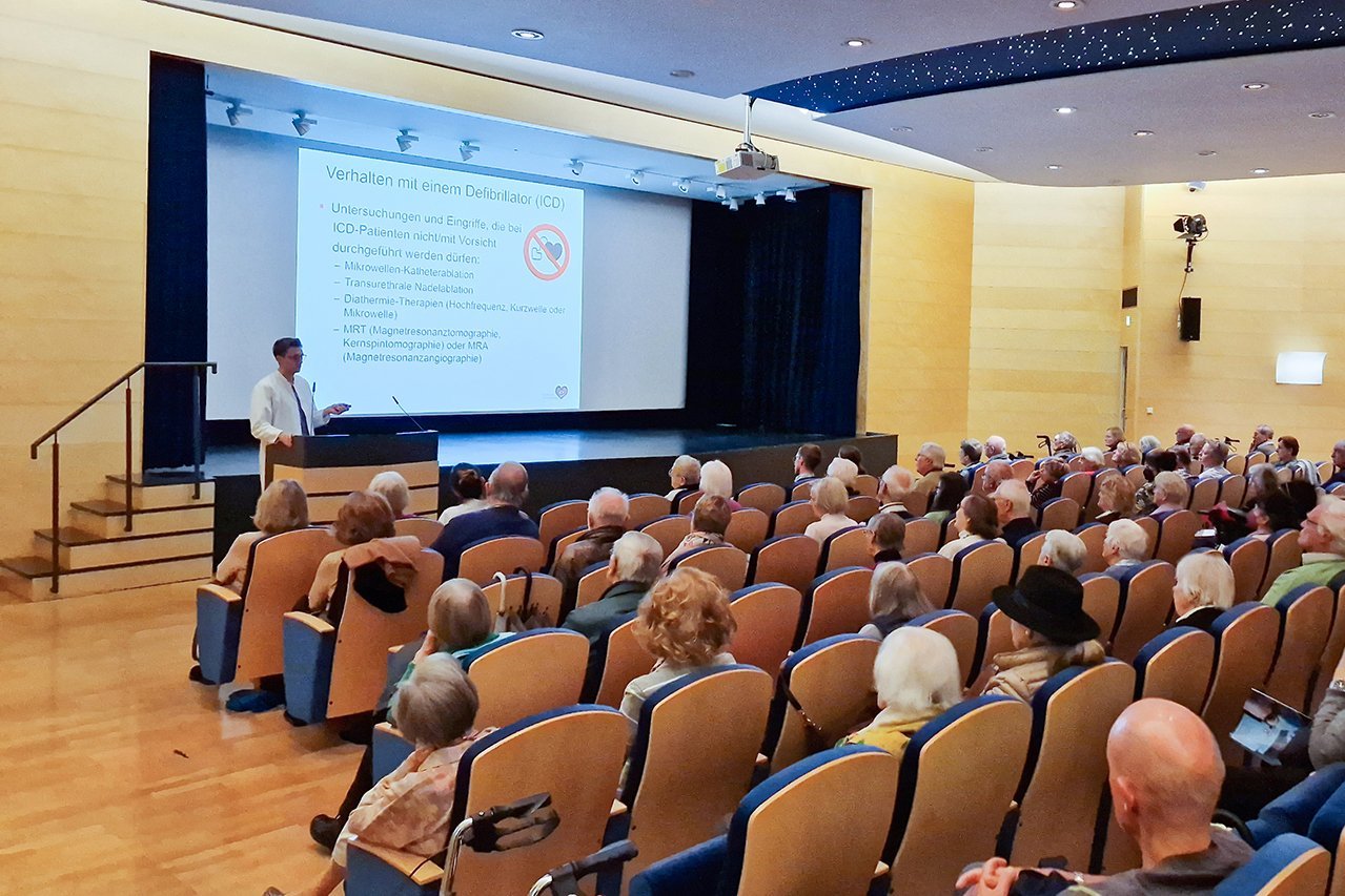 Besucher*innen sitzen im Theatersaal während Dr. Renz einen Vortrag hält