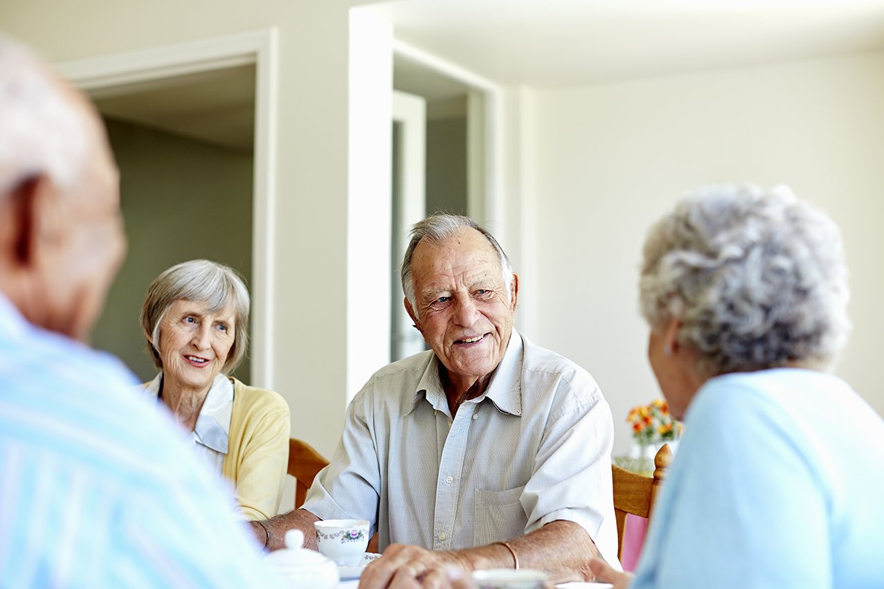 Senior*innen sitzen an einem Tisch und unterhalten sich 