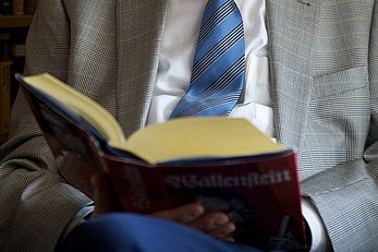 aufgeschlagenes Buch auf dem Schoß eines Mannes
