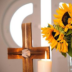 Ein Kreuz und daneben ein Strauß Sonnenblumen auf einem Altar
