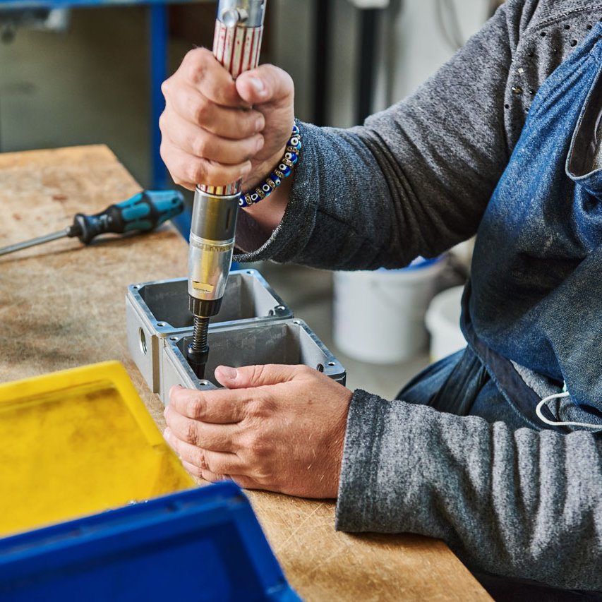 Eine Klient*in montiert eine Schraube an einem Metallteil