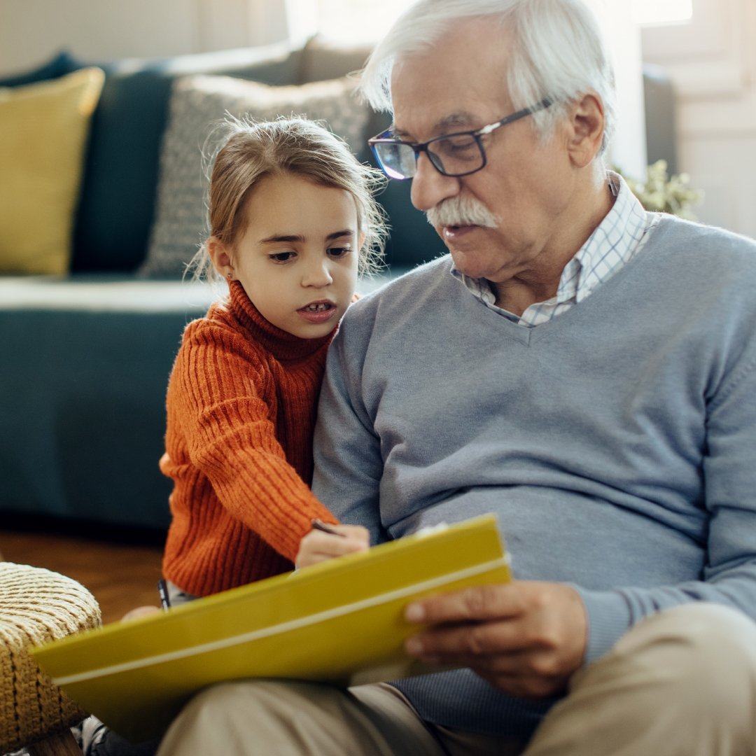Stiften und Vererben Älterer Mann der einem Kind auf dem Sofa sitzt und ihm etwas zeigt