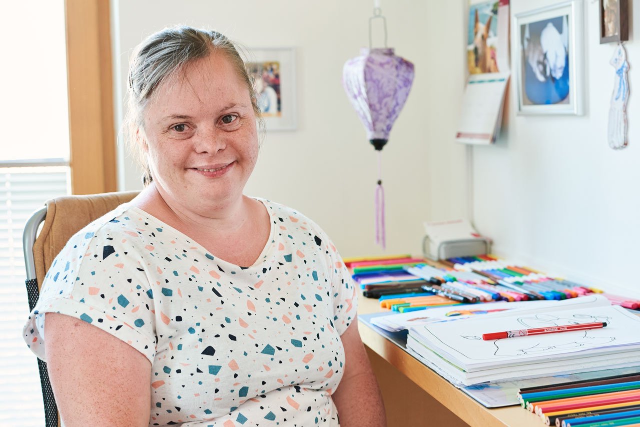 Eine Frau sitzt am Schreibtisch in einem Zimmer