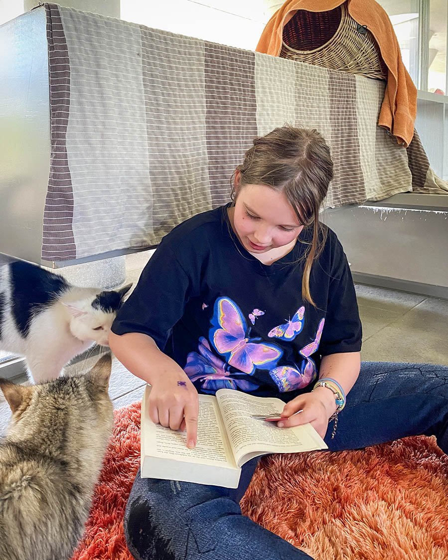 junges Mädchen liest einer Katze aus einem Buch vor