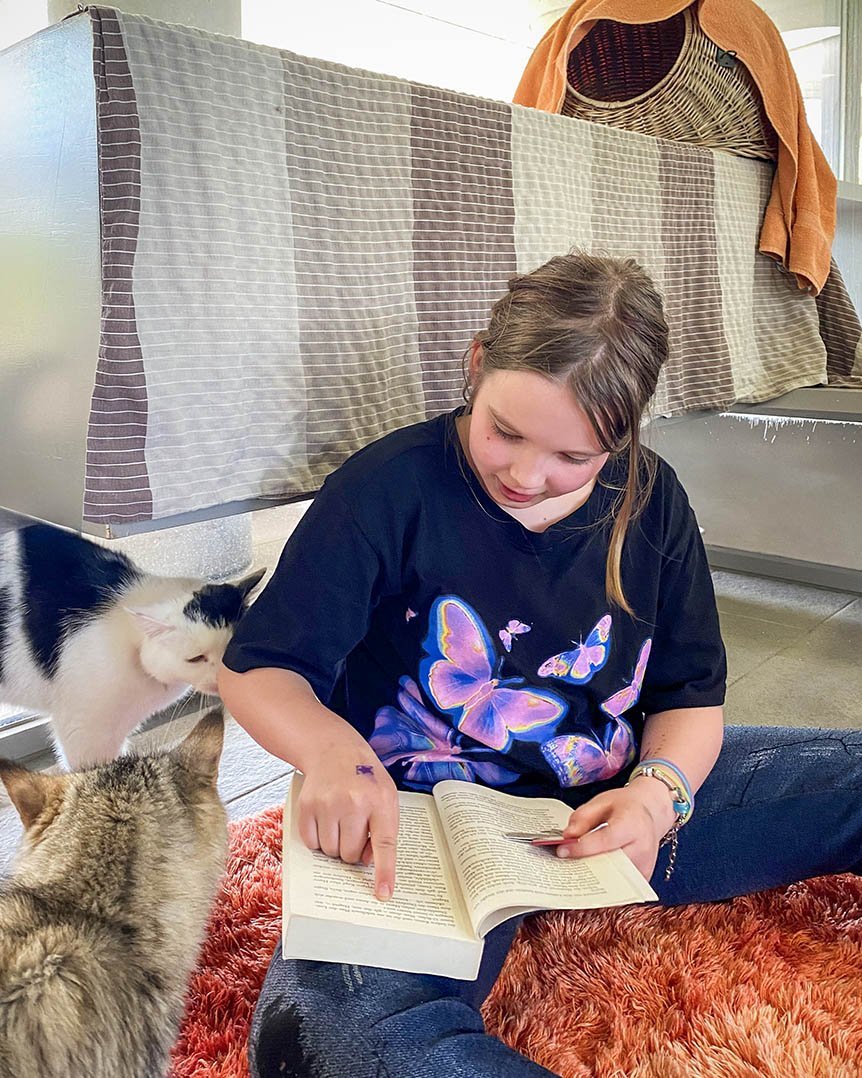 junges Mädchen liest einer Katze aus einem Buch vor