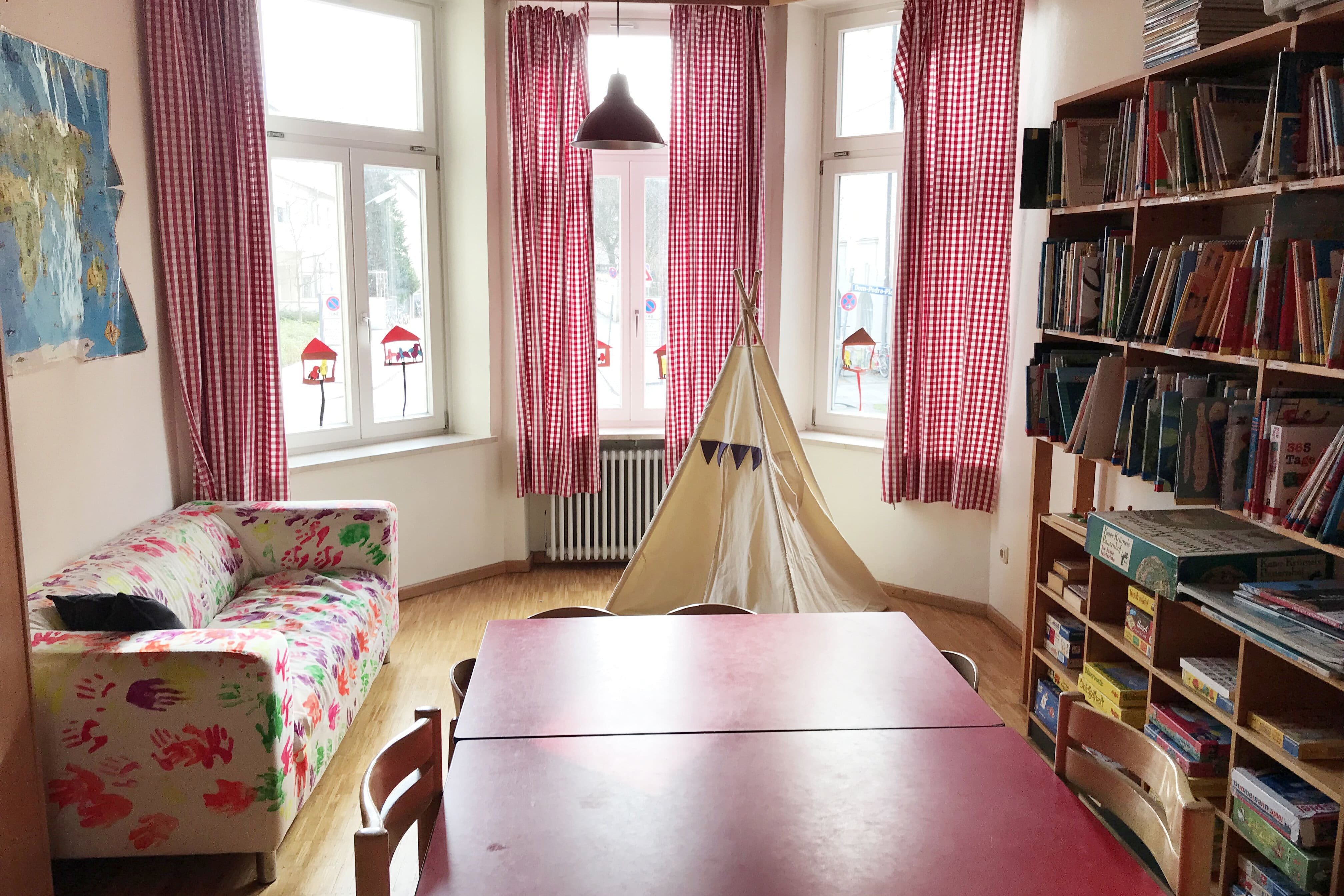 ein Sofa, ein Tisch und ein Spiel- und Bücherregal im Innenraum des Kindergartens 
