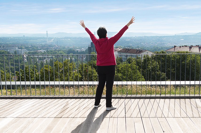 Qi Gong Frau mit ausgestreckten Armen auf einer Dachterrasse