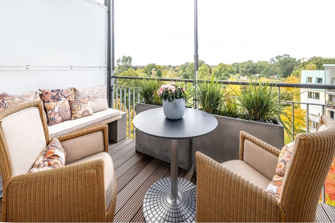 Gemütliche Sitzmöglichkeiten, ein Tisch und Pflanzen auf einem Balkon 