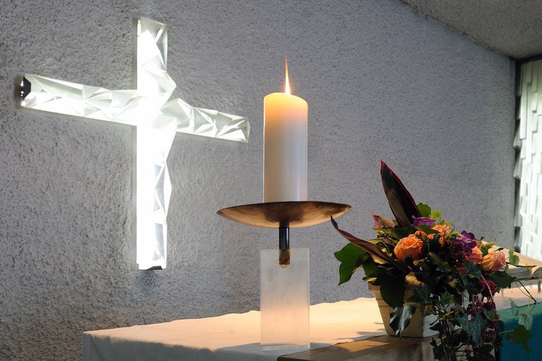 Ein Kreuz, eine Kerze und ein Blumenstrauß