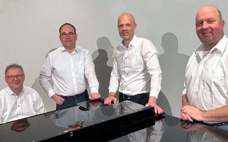Haustechniker Arne Schwämmle mit seiner Band an einem Piano stehend