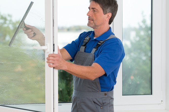Mann mittleren Alters beim Fensterputzen