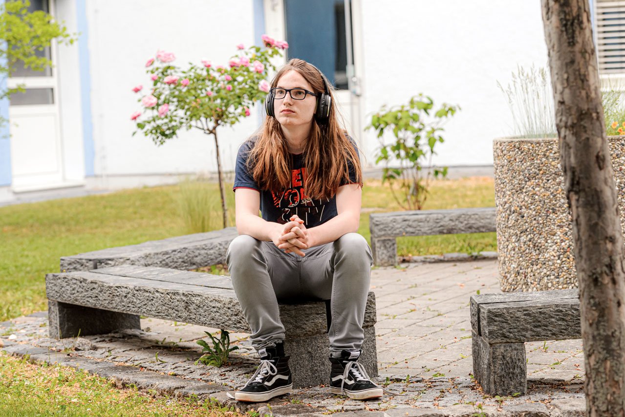 Gartenanlage Ein Jugendlicher sitzt im Garten des Augustinum Studienheims