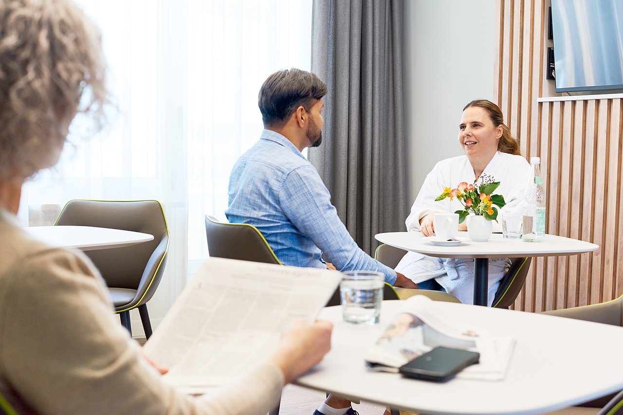 Eine Patientin und ein Besucher sitzen an einem Tisch in der Lounge der Wahlleistungsstation 