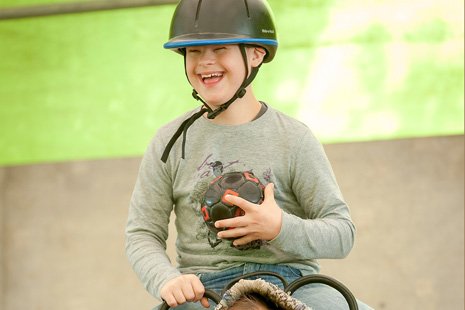 Ein Junge beim therapeutischen Reiten 