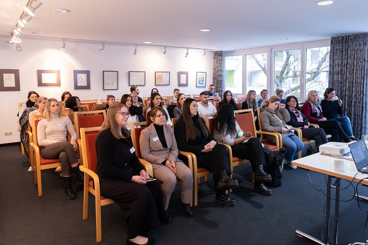 Teilnehmer*innen eines Workshops sitzen auf Stühlen und blicken nach vorne