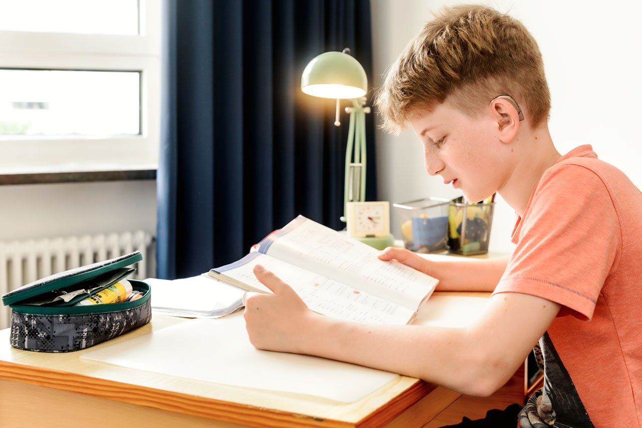 Einzel- oder Doppelzimmer Ein Junge sitzt an seinem Schreibtisch und liest