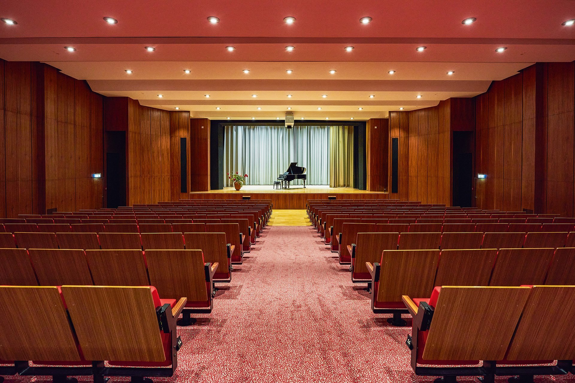 Die Sitze in einem Theatersaal mit Blick auf die Bühne, auf der ein Flügel steht