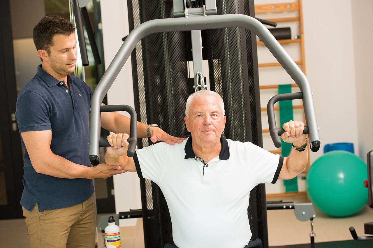 Fitnesstrainer und Bewohner des Augustinum beim Gerätetraining