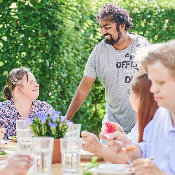 Eine Gruppe von Bewohner*innen beim Mittagessen im Garten