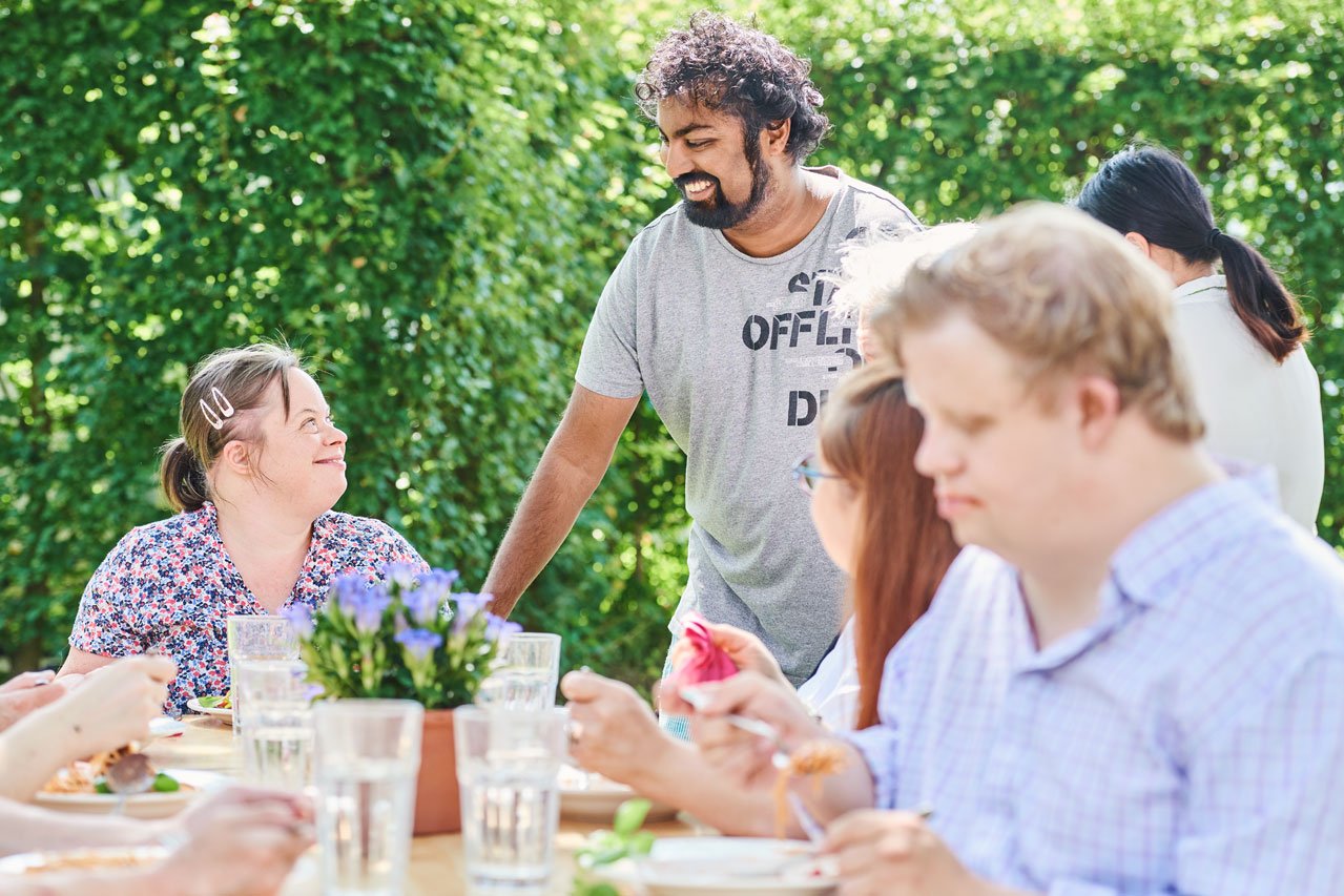 Eine Gruppe von Bewohner*innen beim Mittagessen im Garten