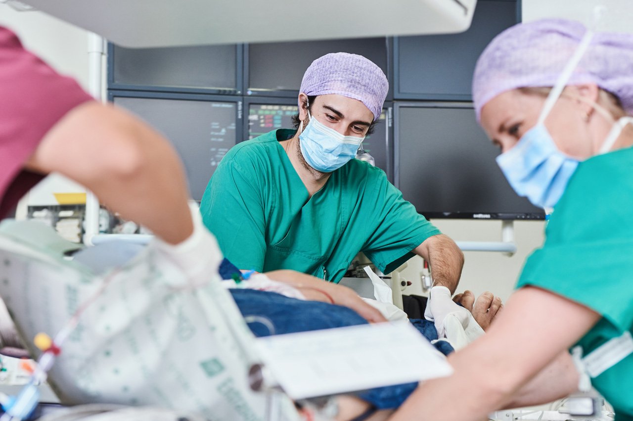 Zwei Pflegekräfte versorgen einen Patienten nach einem kardiologischen Eingriff