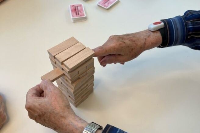 Ein*e Senior*in und ein*e Mitarbeiter*in des Augustinum spielen gemeinsam Jenga