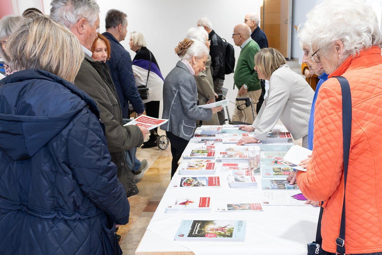 Besucher*innen der Veranstaltung lesen Broschüren und informieren sich an einem Stand der Deutschen Herzstiftung