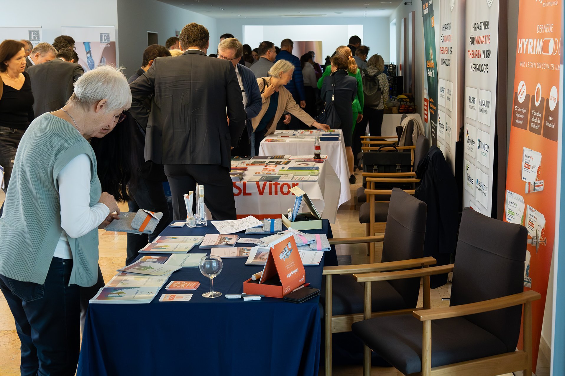 Besucher*innen informieren sich im Foyer an Tischen zu den Sponsoren der Veranstaltung