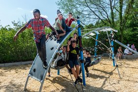 Kinder und Jugendliche sitzen auf einem Klettergerüst