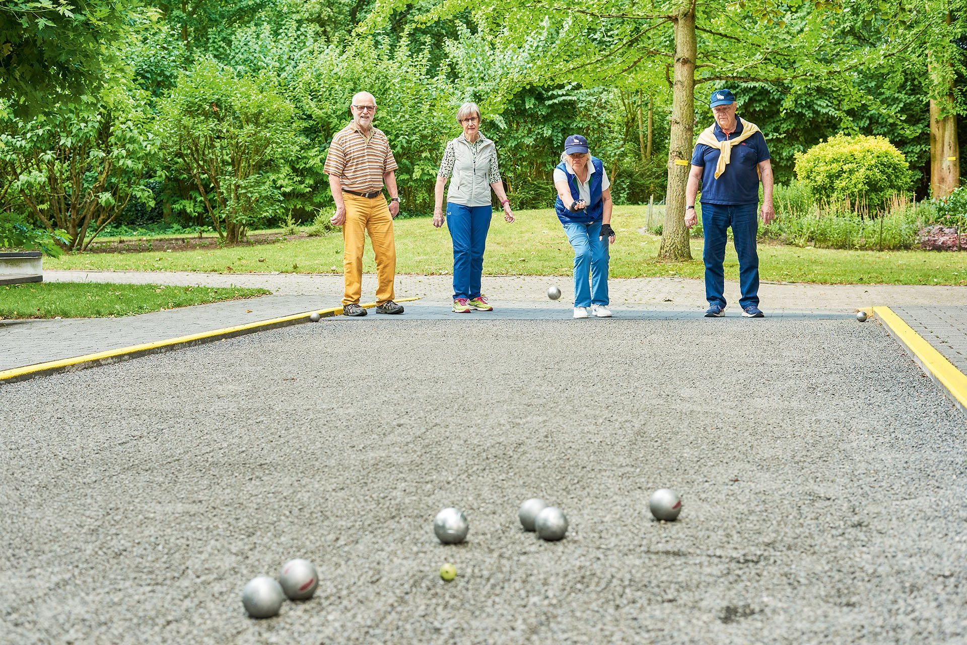 Vier Senior*inne spielen im Außenbereich der Seniorenresidenz Boule