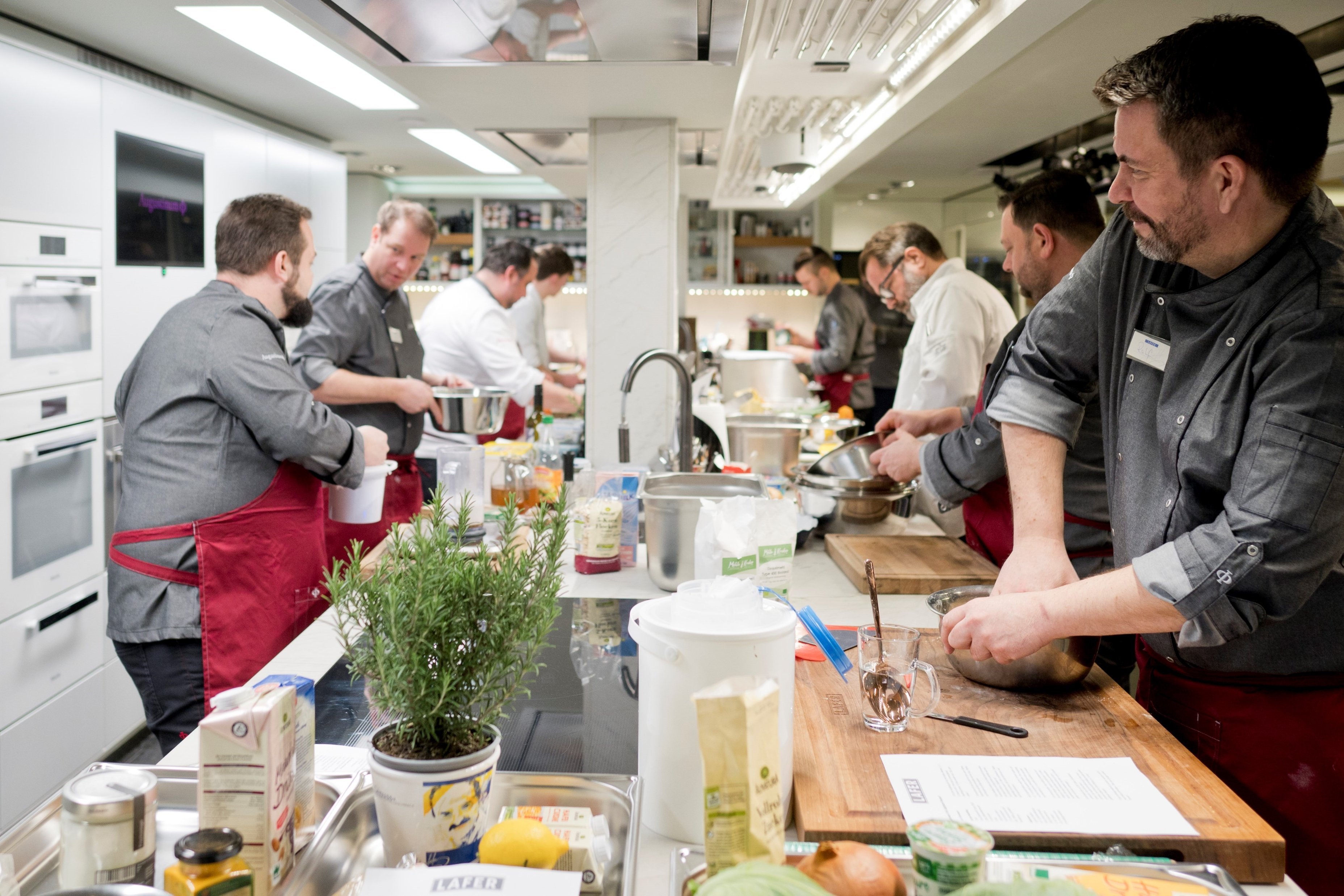 Die Köche der Augustinum Gastronomie beim gemeinsamen Kochen am einem breiten Kochblock