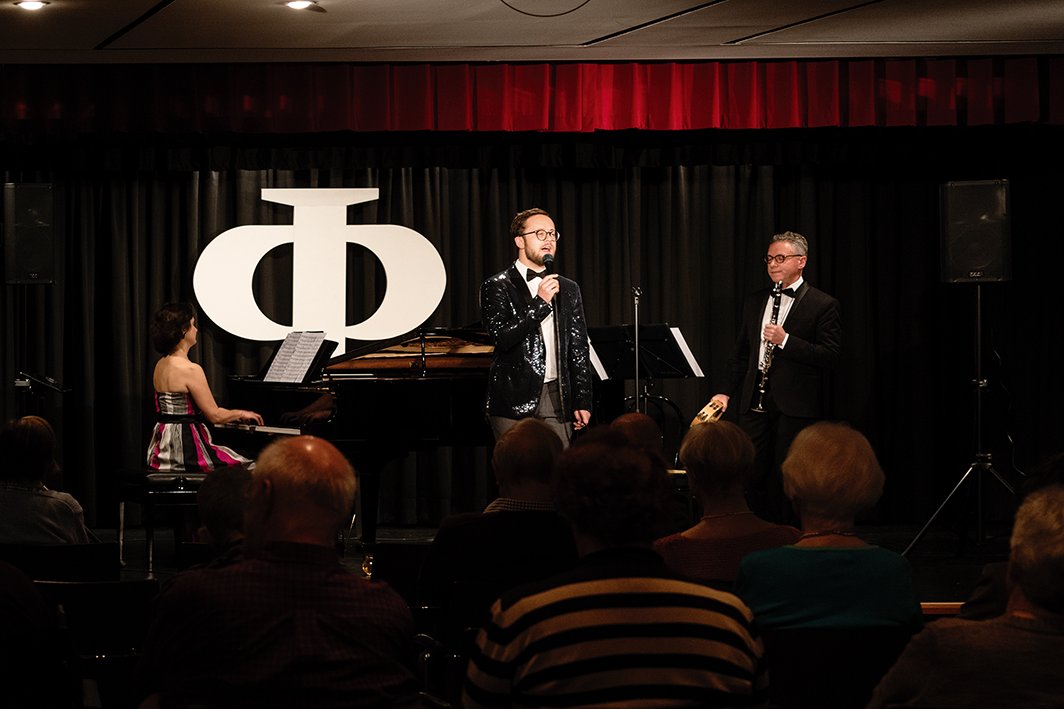 Ein Sänger, eine Pianistin und ein Klarinettist auf einer Bühne 