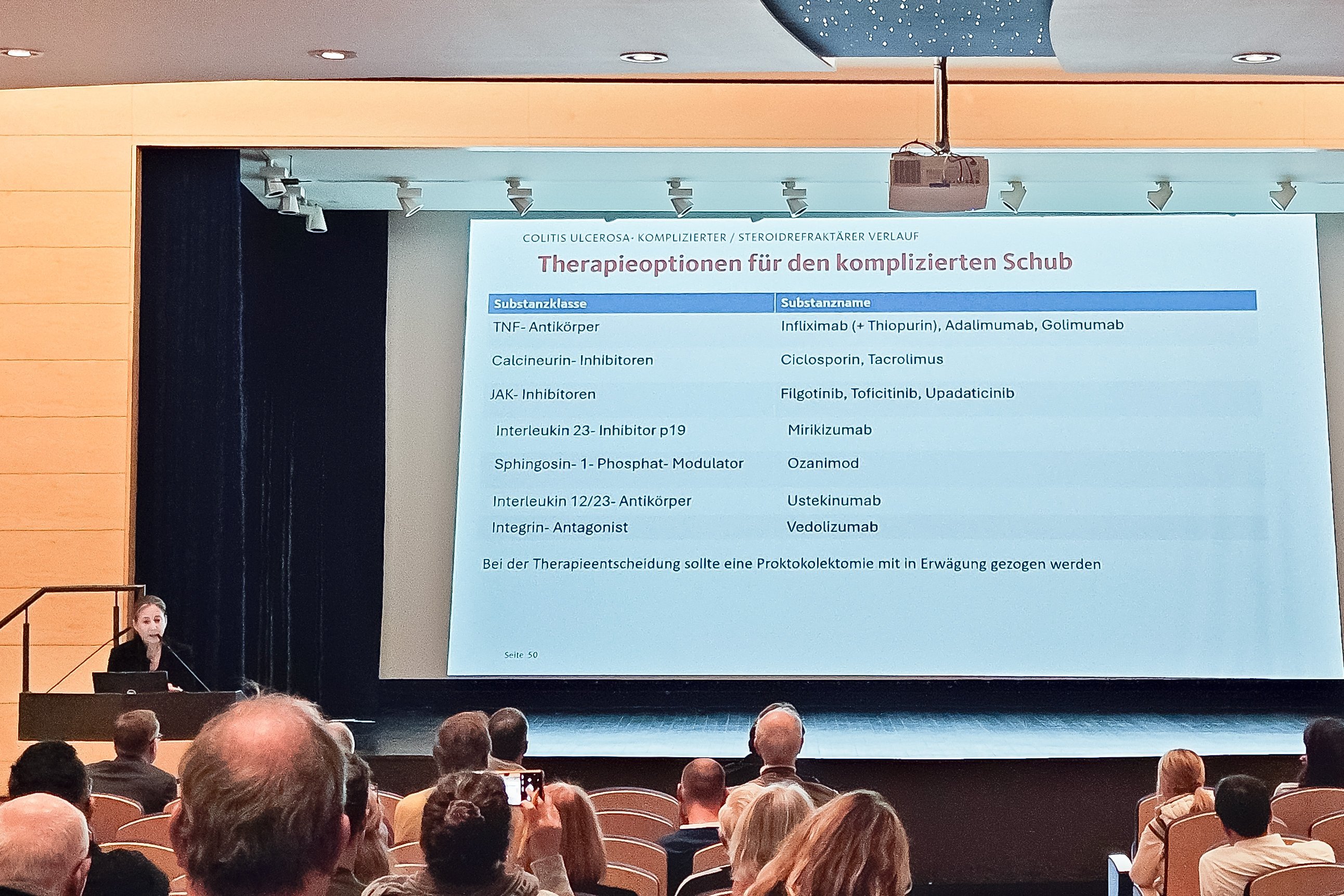 Eine auf eine Leinwand projizierte Präsentation, daneben die Referentin Frau Dr. Ziegler