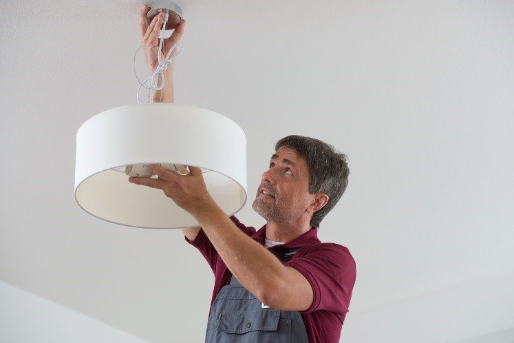 Handwerker beim Befestigen einer Deckenlampe