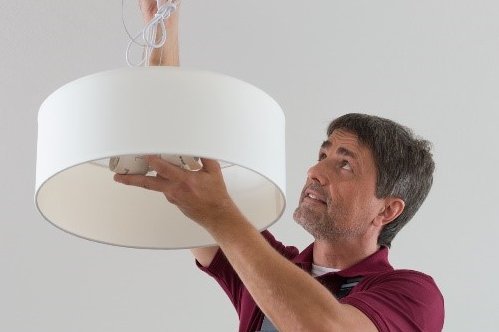 Handwerker beim Befestigen einer Deckenlampe