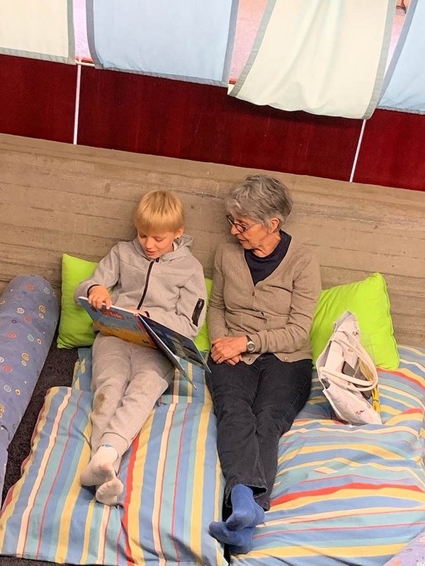 Lesepatin und Schulkind lesen zusammen ein Buch