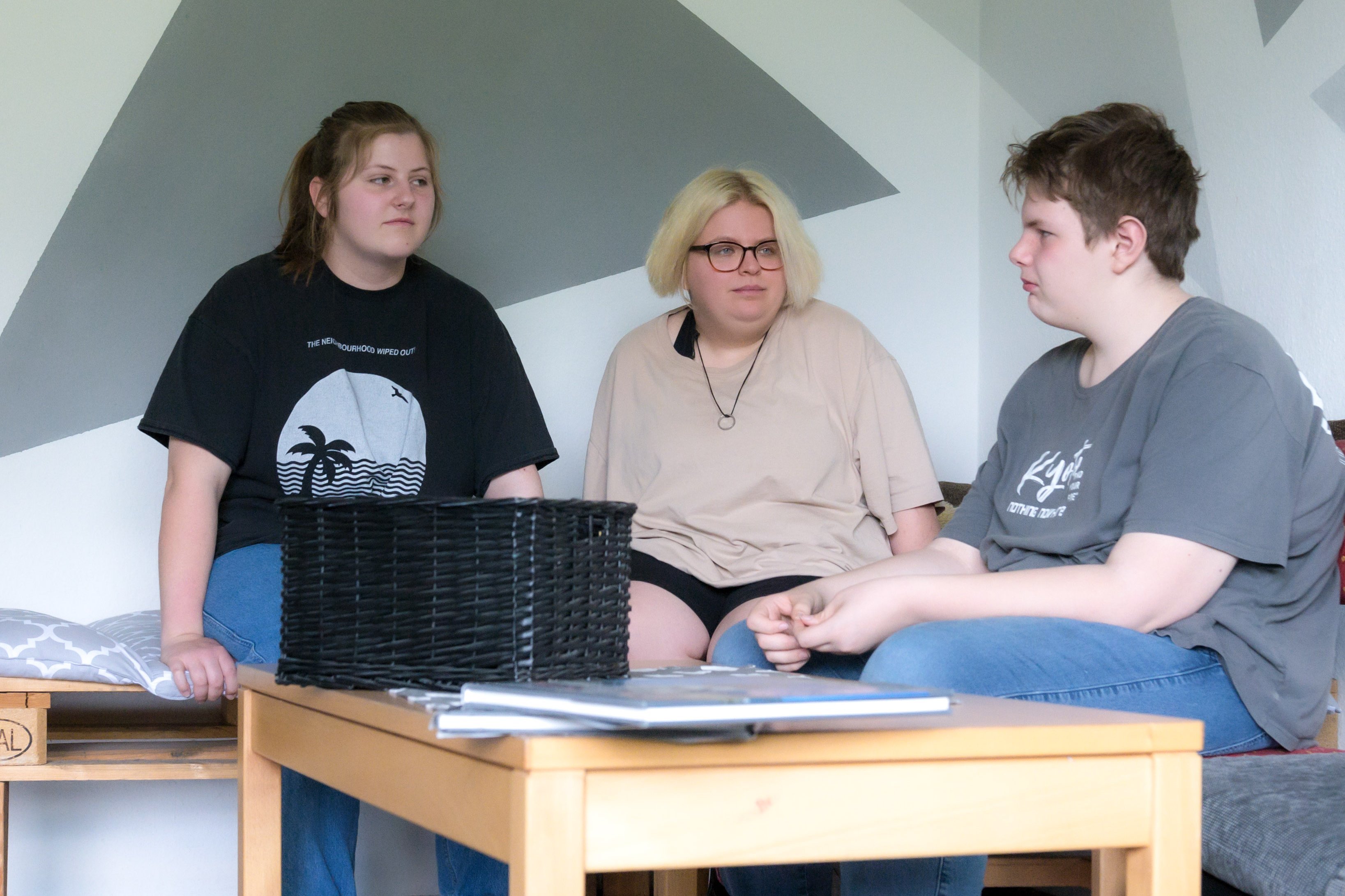 Drei Jugendliche sitzen auf einem Sofa und sprechen miteinander