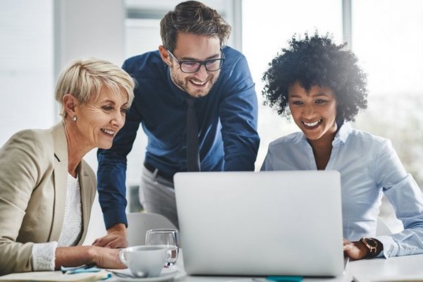 Kolleg*innen schauen gemeinsam auf einen Laptop