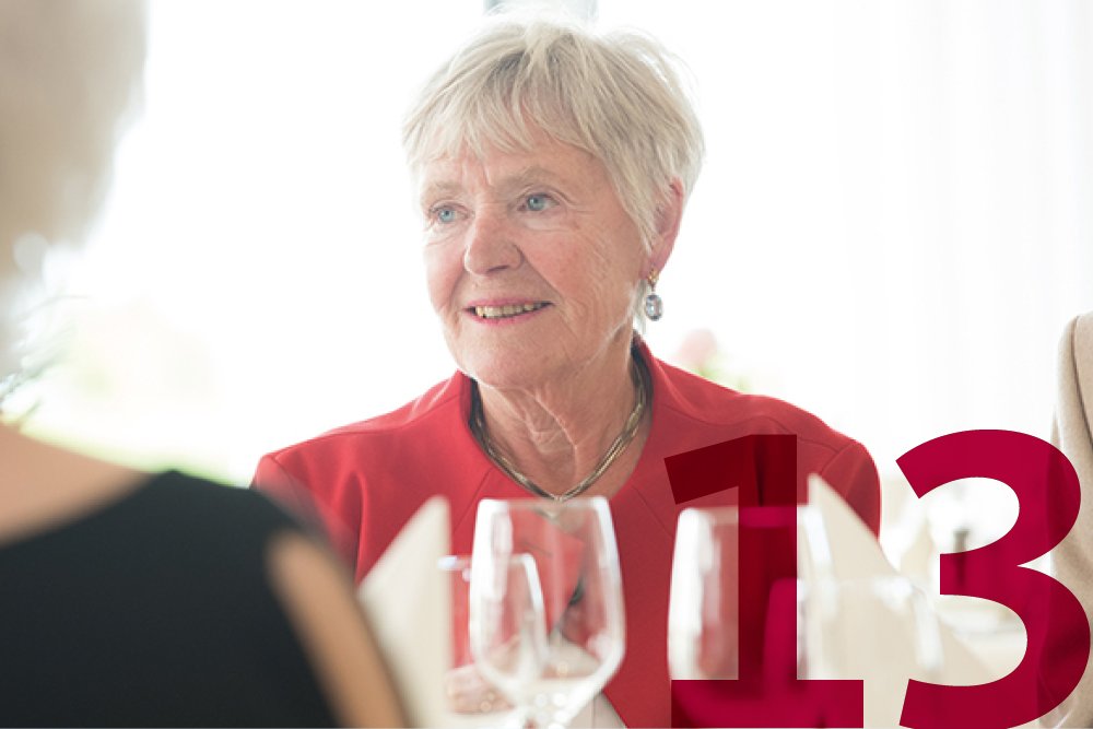 Eine Seniorin sitzt an einem gedeckten Tisch 
