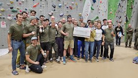 Ein Gruppenfoto der Gebirgsjäger vor einer Kletterwand mit dem Spendenscheck für den Augustinum Kindergarten 