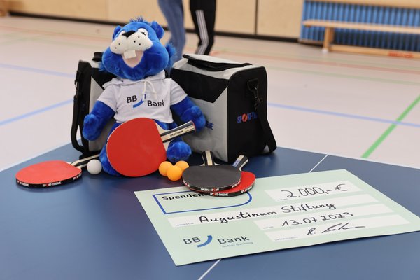 Der Spendenscheck, Tischtennisschläger und ein Kuscheltier der BBBank auf einer Tischtennisplatte